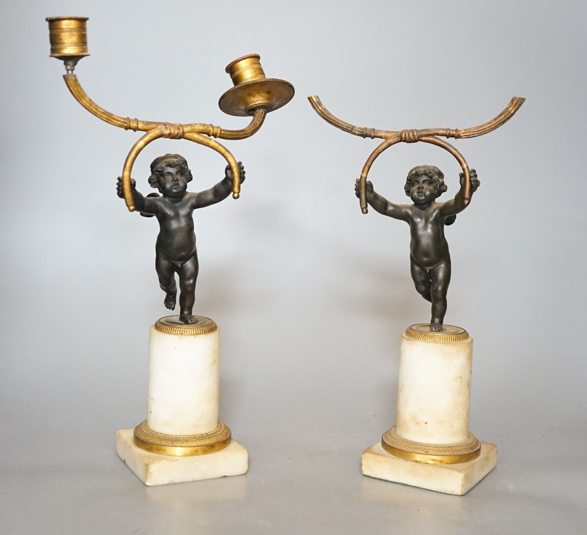 A pair of 19th century bronze and ormolu cherub candelabra, on alabaster plinths, 33cm